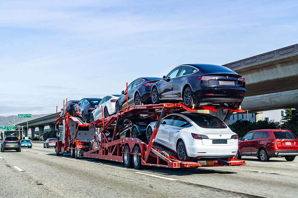 cars in open trailer ready for shipping long distance