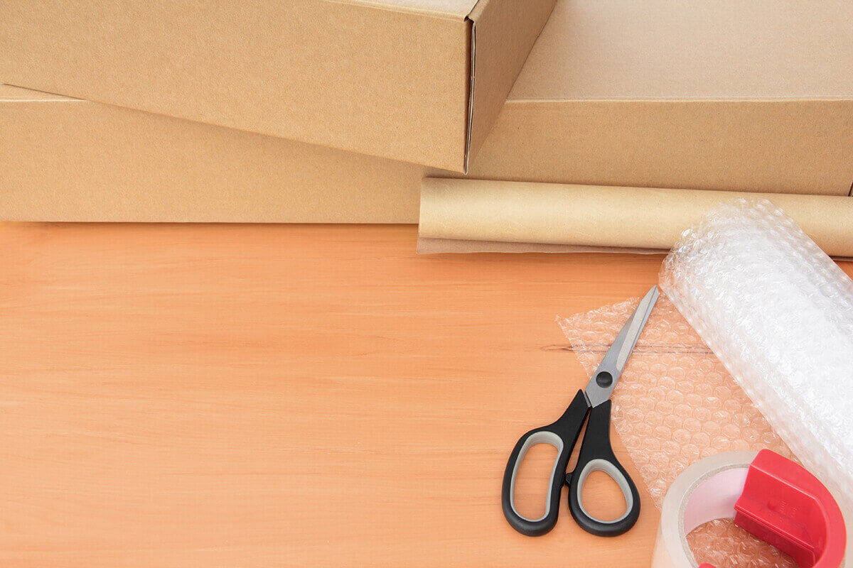 scissors, duct tape, and bubble wrap sitting in a box, ready for long-distance moving