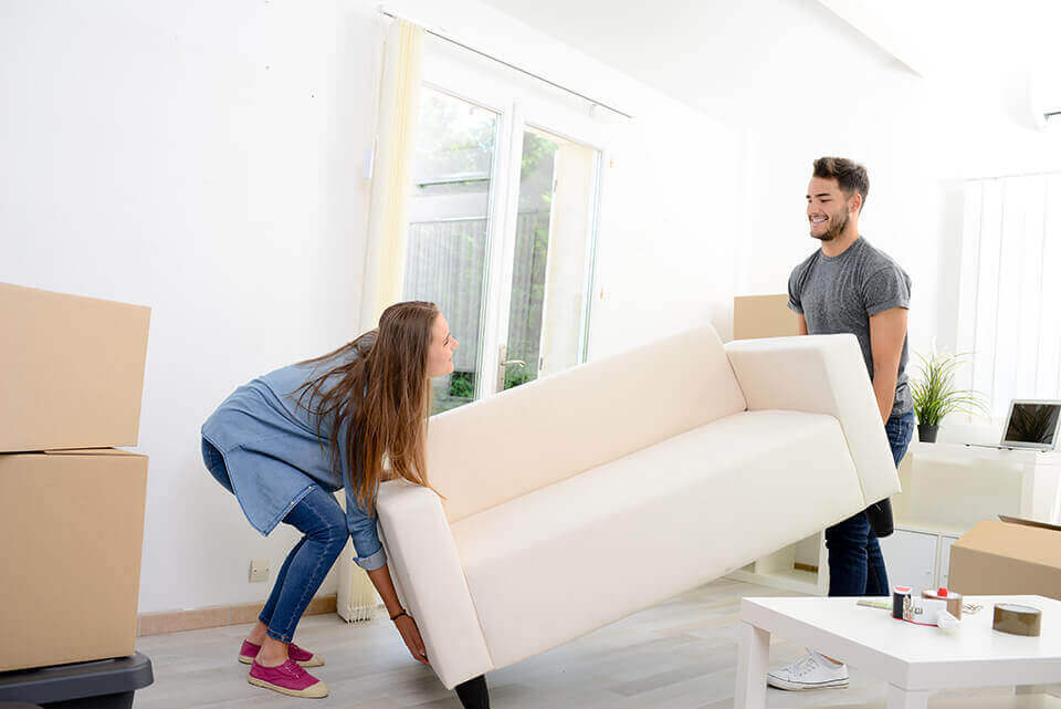 People carrying a large couch which would be way eaiser if they use cross country moving services