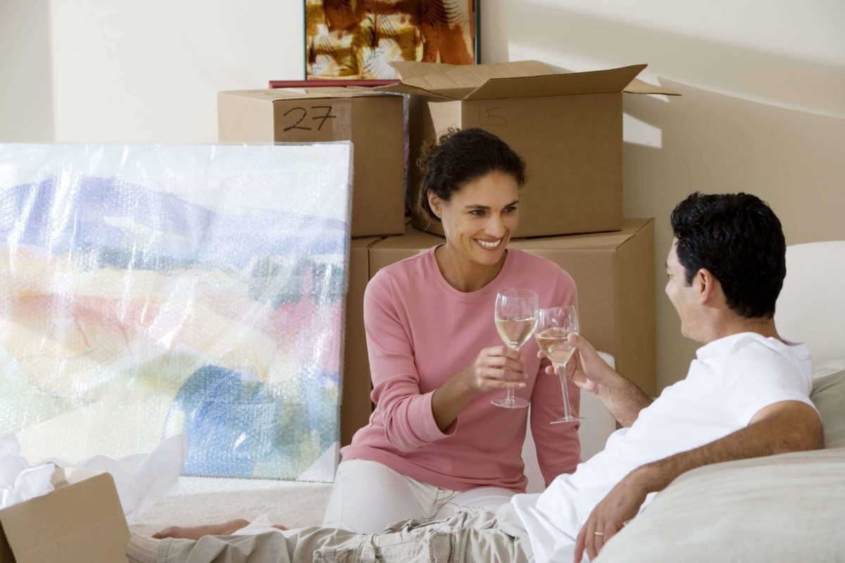Two people raising a toast while sitting on the floor in the middle of unpacking