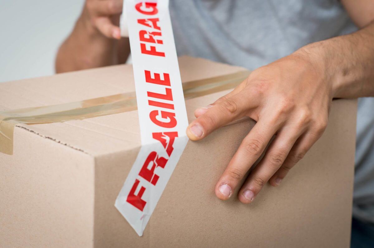 A guy putting a fragile label on a box