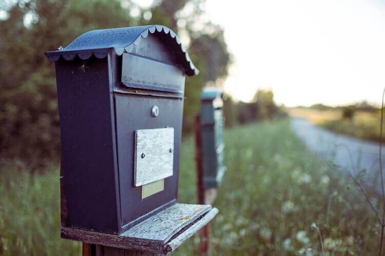 A gray mailbox on the road