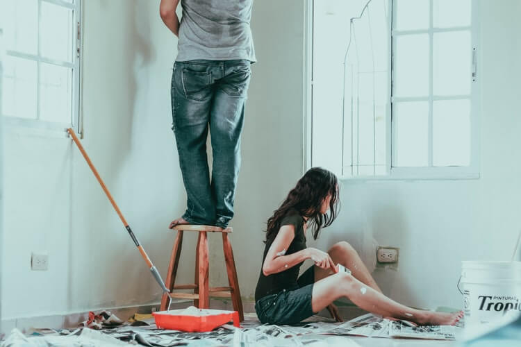 two people in a relationship painting a room after moving cross-country