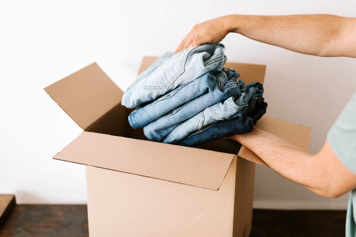 a woman putting clothes in a box getting ready for long-distance moving