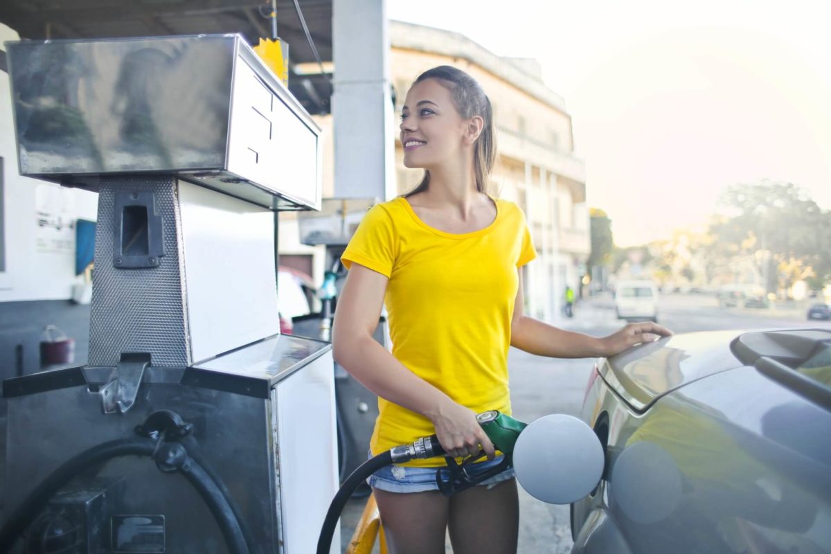 Girl pumping gas in a vehicle before long-distance moving