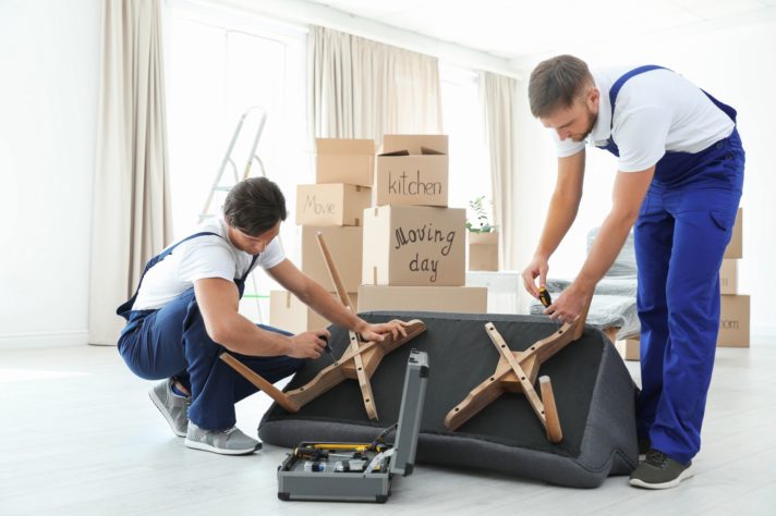 Long-distance movers disassembling a sofa