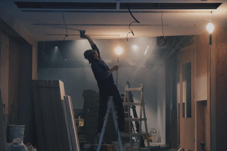 man on a ladder fixing up ceiling