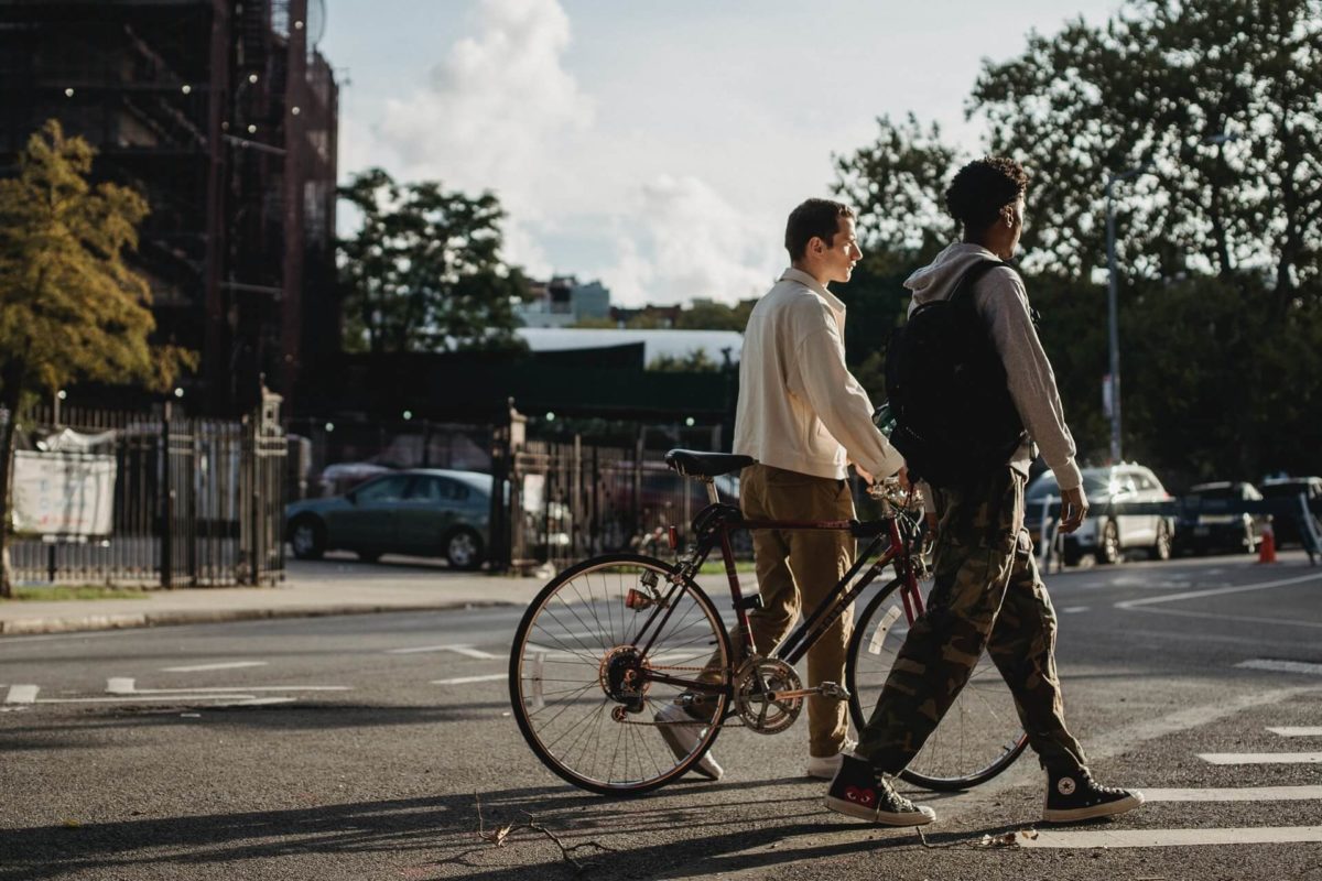 two young guys walking, and one is pushing a bicycle