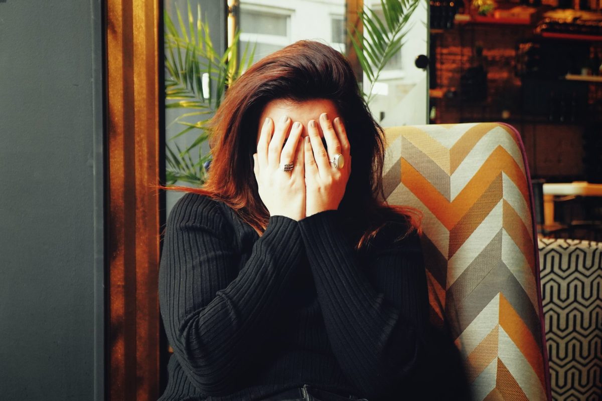 Woman in the black sweater covering her face with her hands