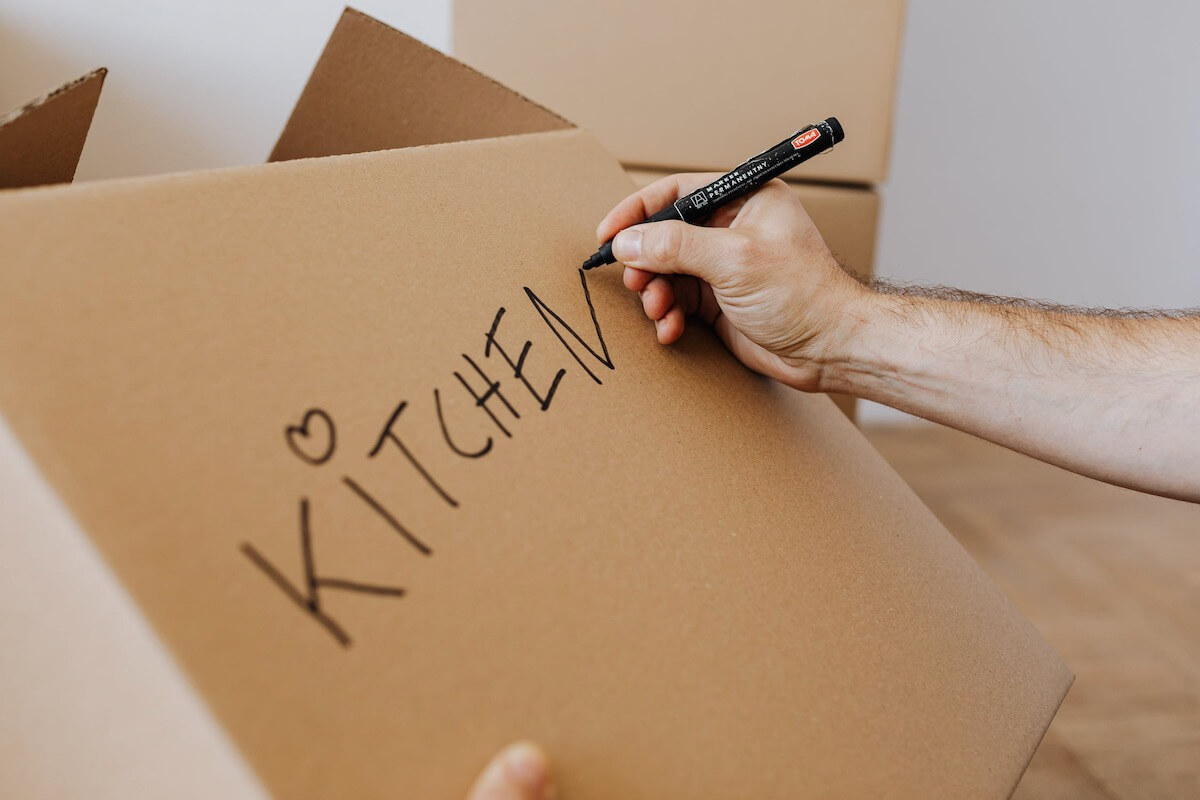 Man is labeling the box with kitchen items