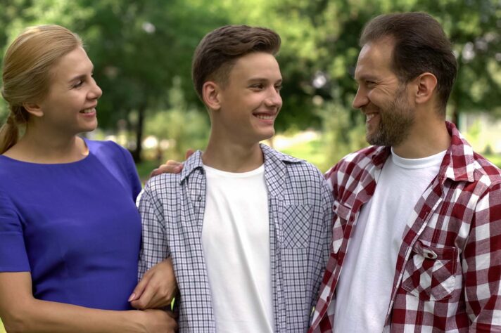 Happy parents looking at teenage son with pride, successful college student