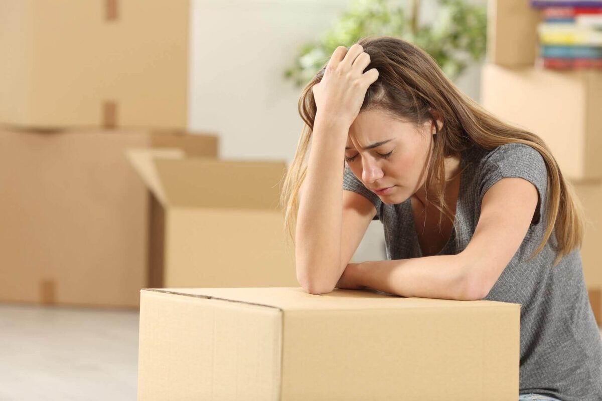 Stressed woman holding her head and leaning on a box before moving cross country