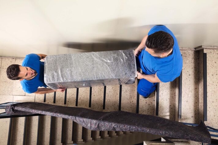 Movers transporting a fridge down the stairs