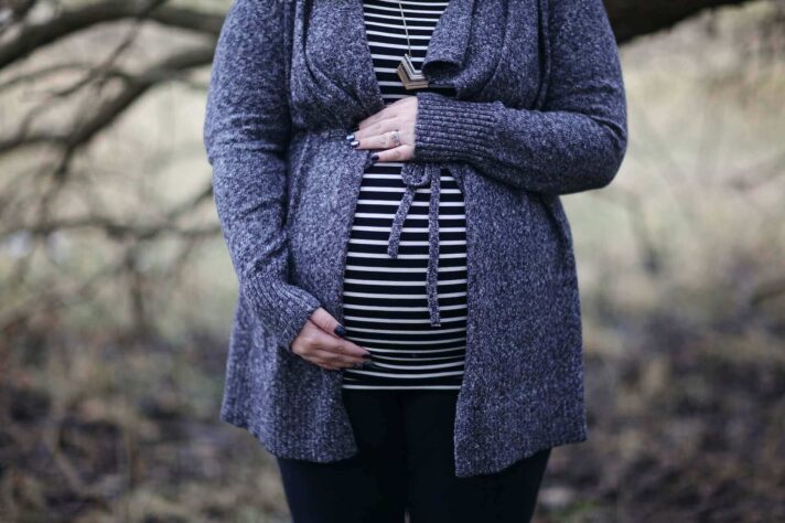 A pregnant woman in a blue cardigan