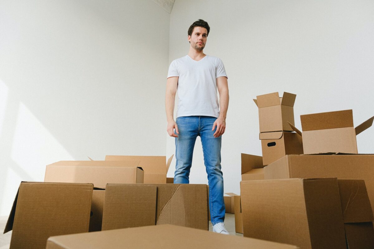 Man standing in the white room amidst cardboard boxes