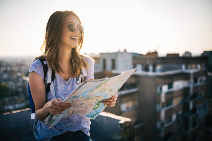 Happy young woman using a city map after long-distance moving