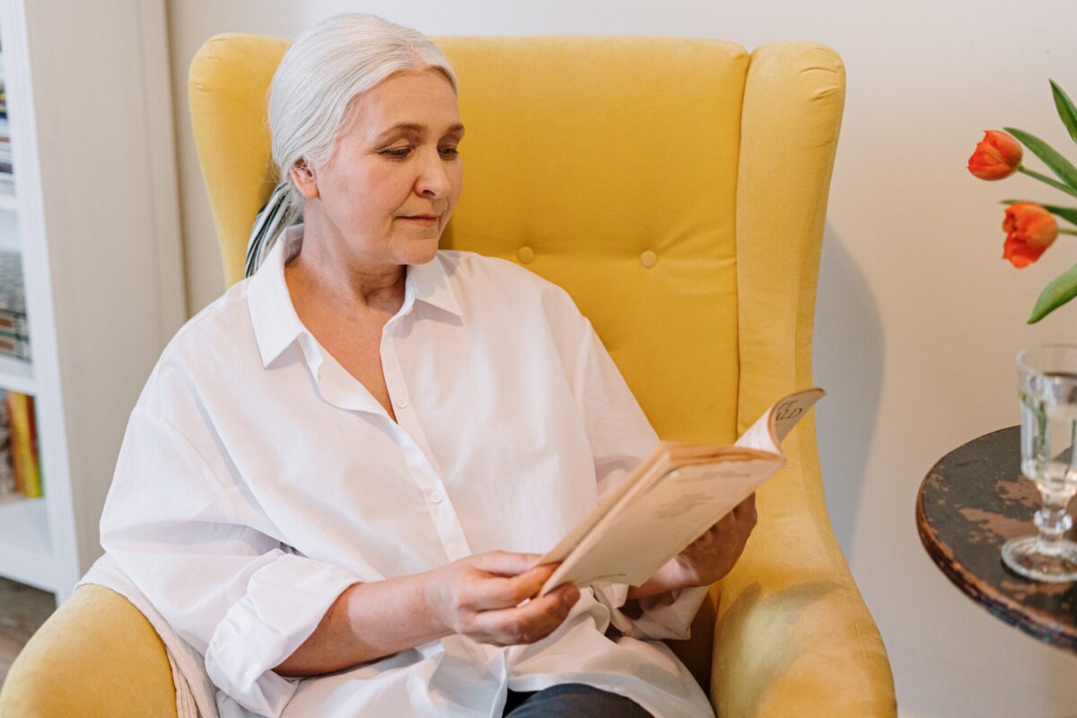 An older woman reading in a chair after long-distance moving
