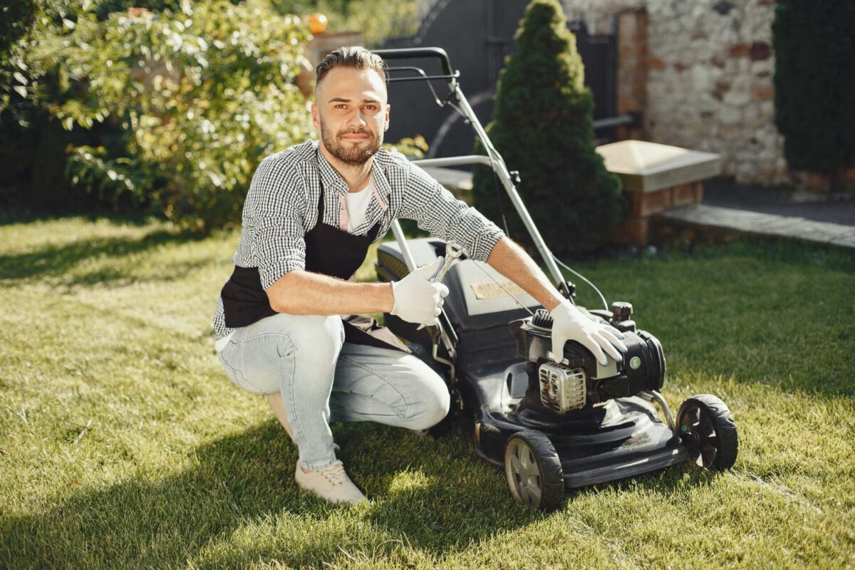 A man next to a lawn mower smiling