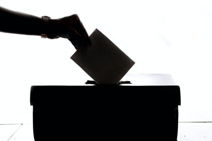 A person putting their ballot into a box