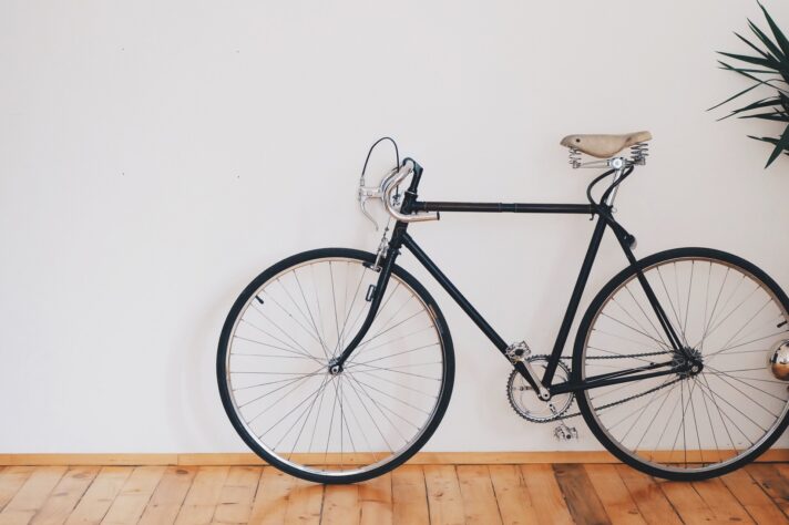 A black bicycle beside a white wall