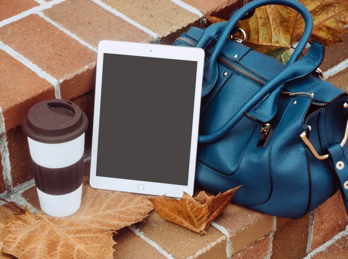 A bag next to a coffee and a tablet