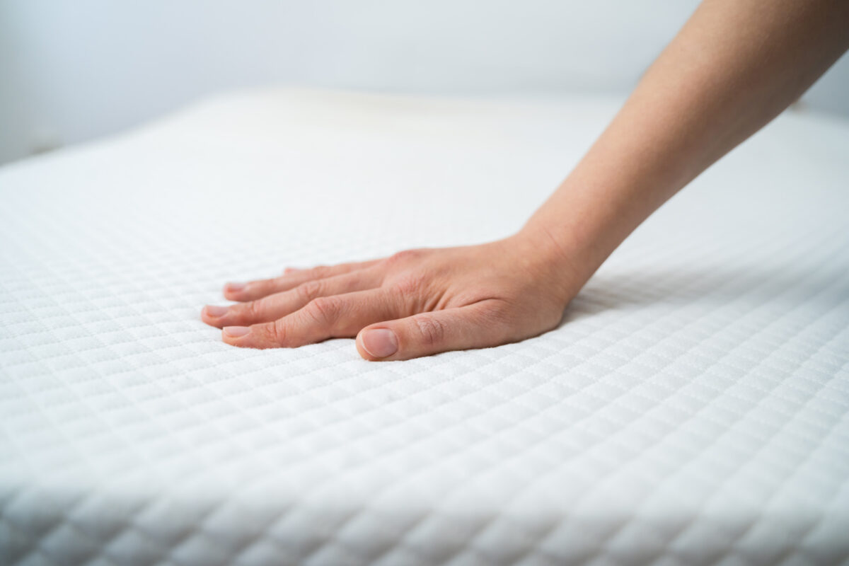 A person placing their hand on a mattress