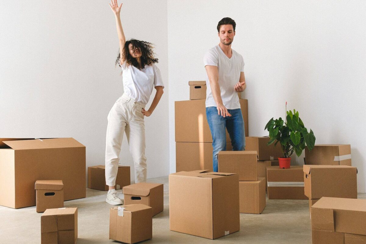 Couple dancing in a room full of boxes after cross-country moving