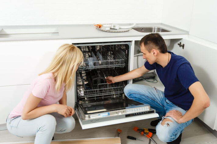A man and a woman standing next to an open dishwasher before moving cross country