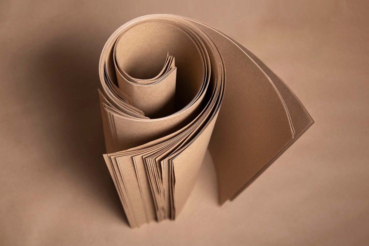 Brown kraft paper twisted into a roll for packaging various products, production of ecological bags, printing on it, top view, selective focus. Kraft paper in the printing industry