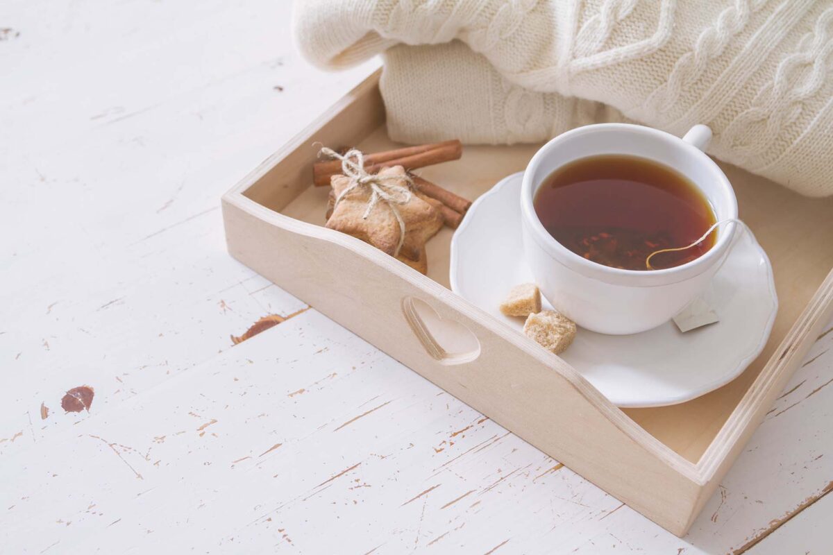 Tea tray and sweater, white wood background, toned