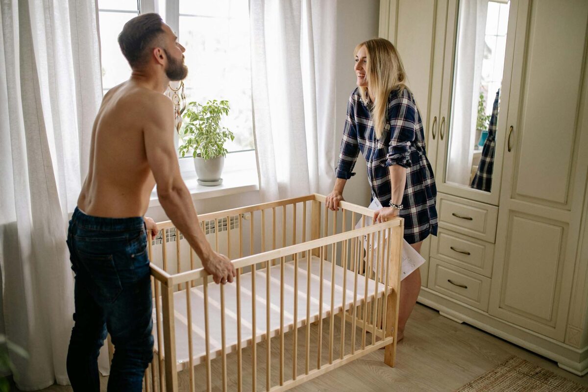 A happy couple moving a baby crib at home