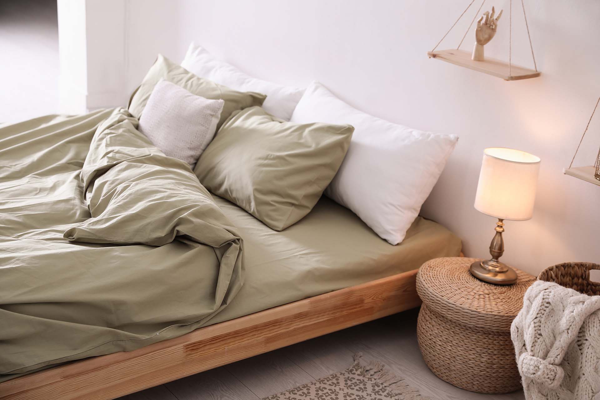 Comfortable bed with olive green linen in modern room interior