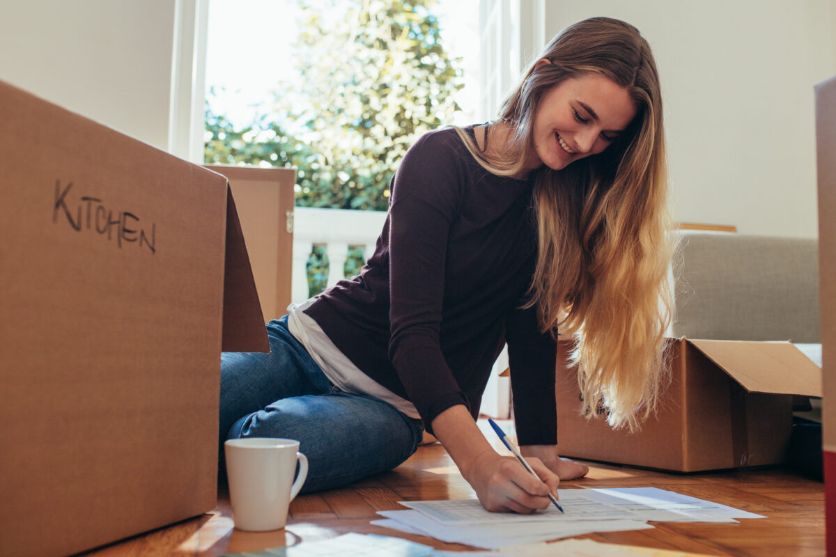 Woman reviewing written moving estimates surrounded by packed boxes